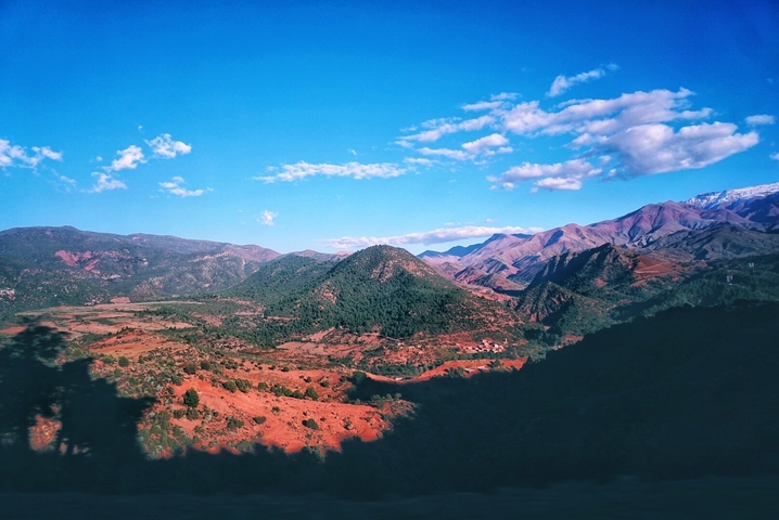 Mountainous landscape with valleys and distant peaks under a blue sky.