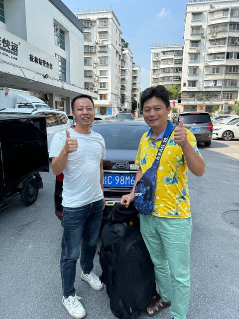 Two people posing on a street with buildings in the background.