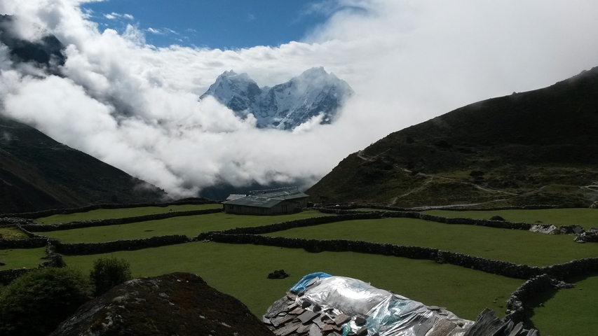       Mountain landscape with scattered houses and clouds.
  