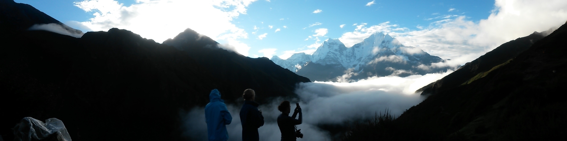 Silhouettes of people capturing a sunrise over the mountains.