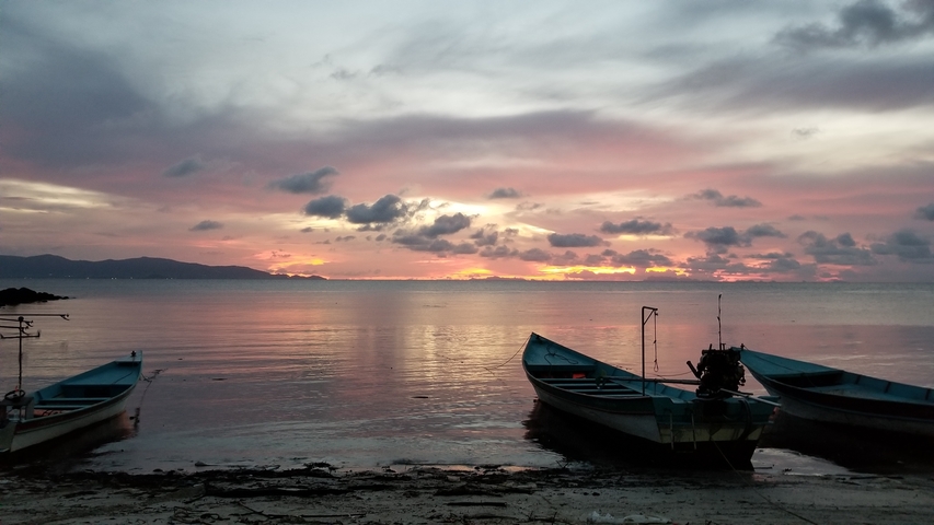 Sunset view over the water with boats in the foreground.