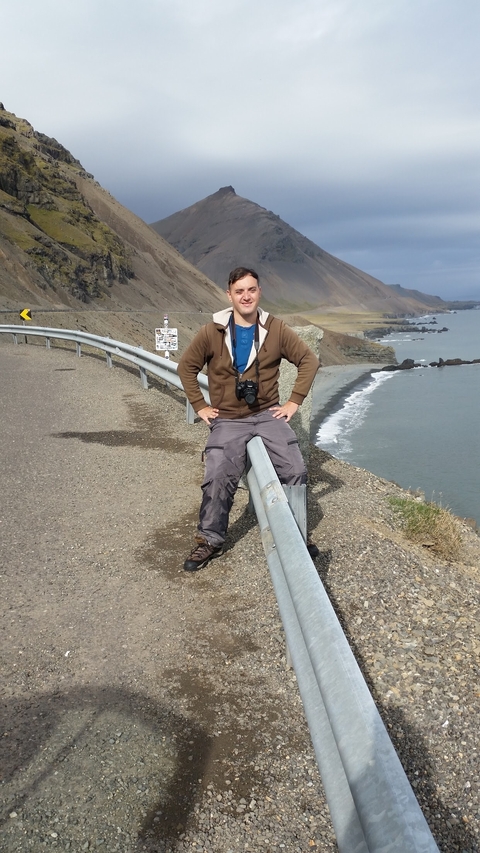 Man sitting on a railing with a coastal view.