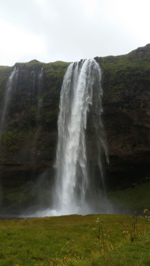Waterfall flowing down a cliff face in cloudy weather.