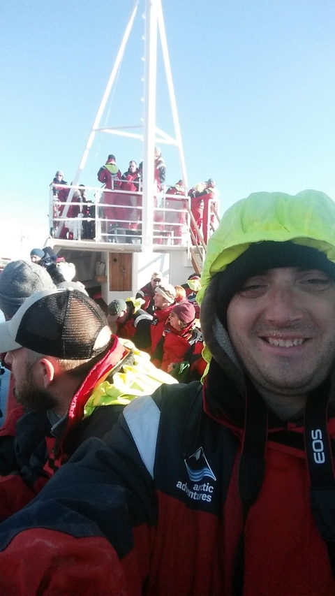 Group of people on a boat wearing colorful jackets.