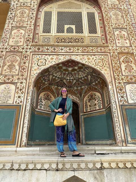       A person posing in front of a beautifully decorated archway.
  