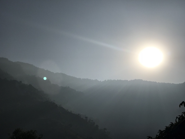 Sun setting over mountain range with lens flare.