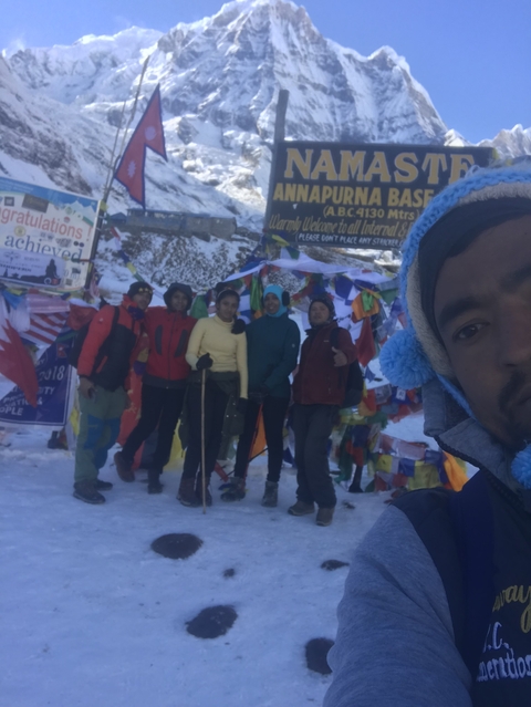 Group of people at a snowy mountain pass with flags and signs.
