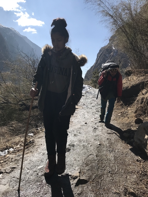 Hikers on a trail with mountainous terrain in the background.