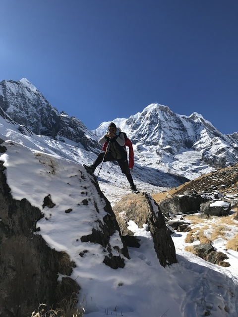 Person posing with trekking poles on a rocky slope in the mountains.