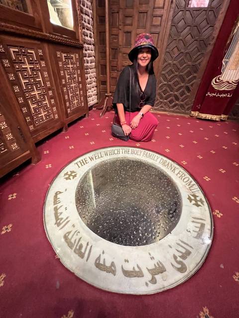 Person sitting by a circular well with Arabic script.