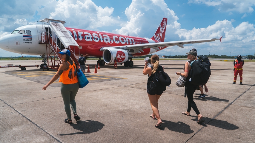 Travelers boarding a plane on an airport tarmac.