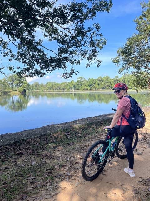       Person cycling on a path beside a large water body.
  