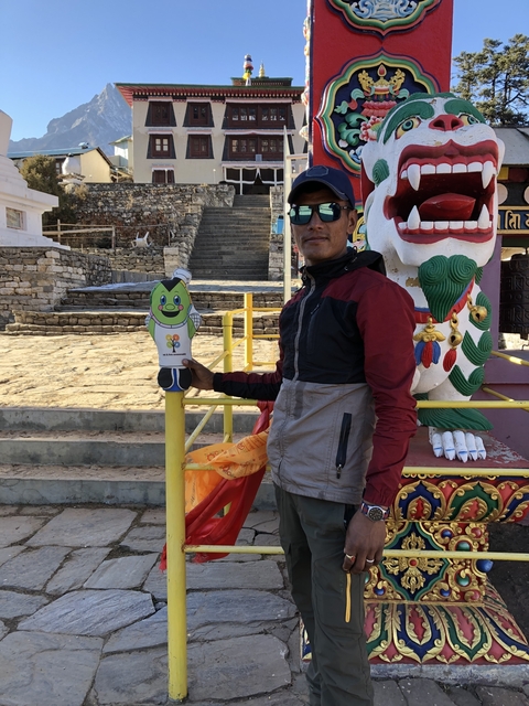 Person standing next to a colorful statue in a mountainous area.