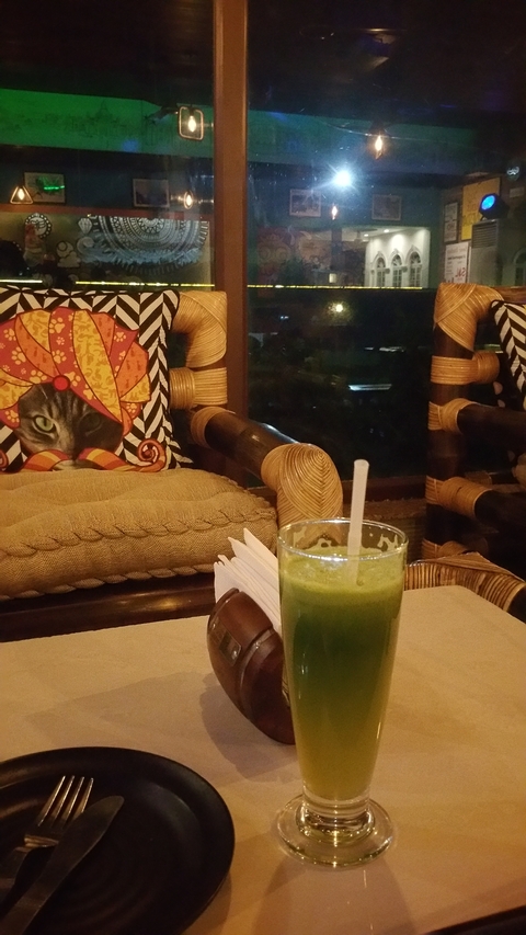 Interior of a cozy room with decorative pillows and a drink on the table.