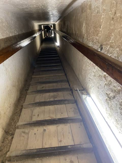       Narrow underground passageway with a person crawling.
  