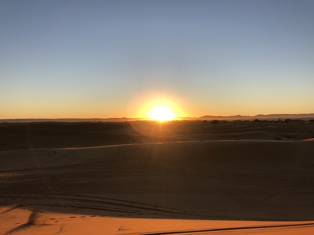 Sunset over sand dunes in a desert.