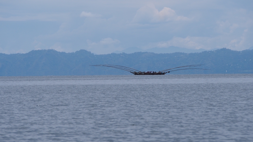       Boat in the distance with mountains visible.
  