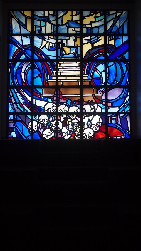       Colorful stained glass window featuring skulls.
  