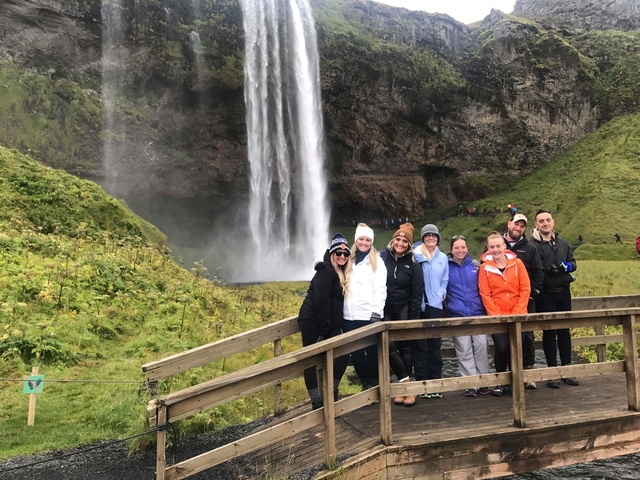 Group of people posing in front of a waterfall.