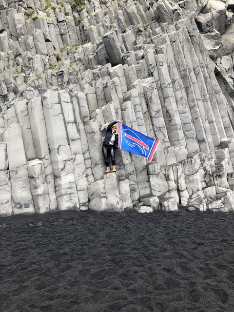       Person holding a flag standing on basalt columns.
  