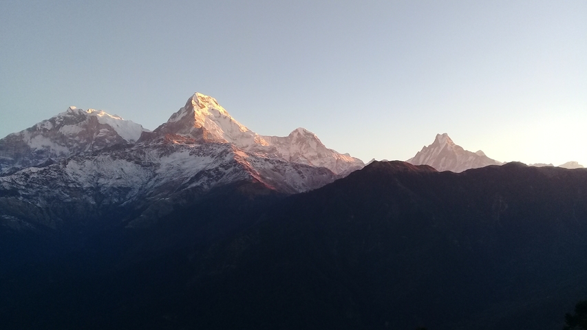 Mountain landscape at sunrise with peaks illuminated by the sun.