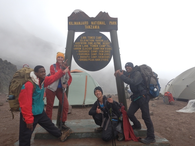       Group posing at a signpost in Kilimanjaro National Park.
  