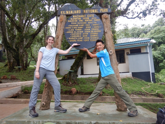       Two people at Kilimanjaro National Park signpost.
  