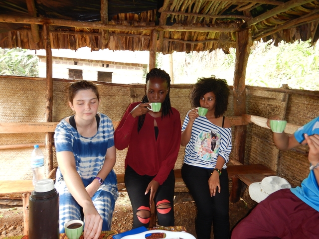       People sitting inside a hut drinking from cups.
  