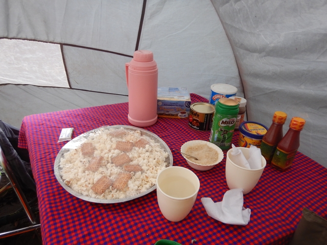       Close-up of a campsite meal setup with snacks and thermos.
  