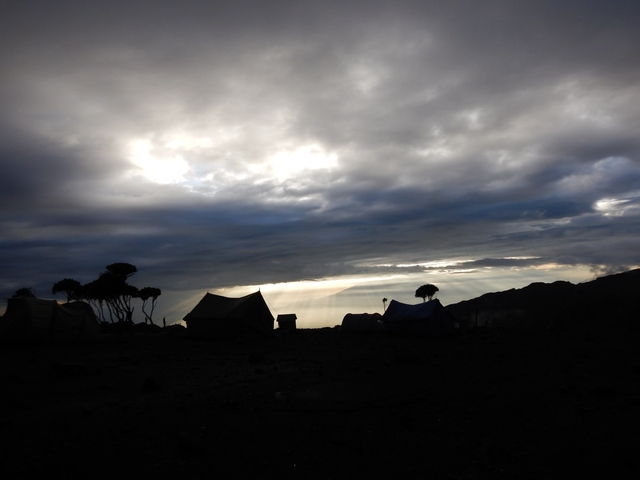       Silhouette of a campsite against a dramatic sky.
  