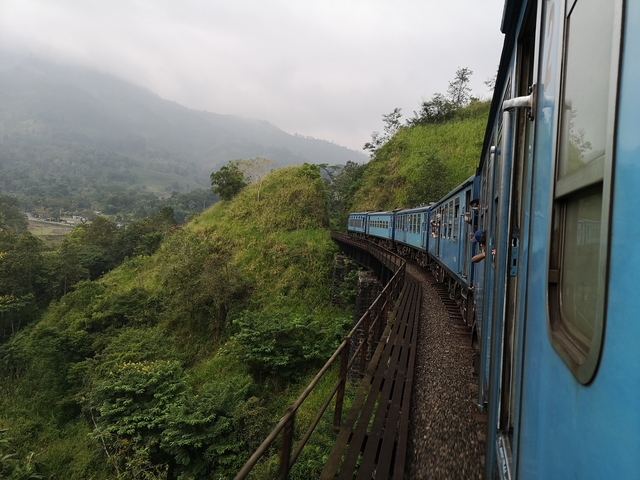      Train passing through a scenic green hillside.
  