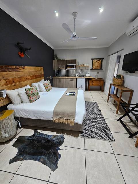 Interior view of a modern bedroom with a bed, ceiling fan, and kitchenette.