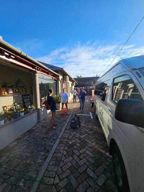       A group of people standing near a van on a brick road.
  