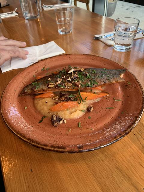 A plated fish dish with vegetables on a wooden table.