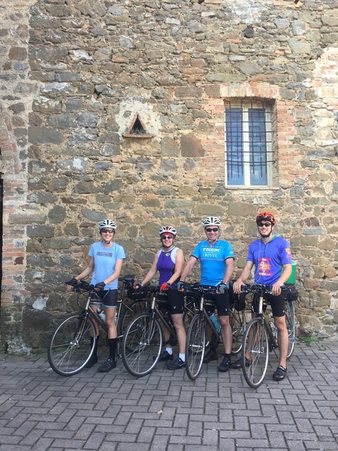 Group of cyclists posing in front of a stone building.