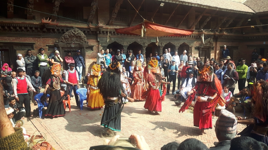       A traditional dance performance with a crowd gathered in a courtyard.
  