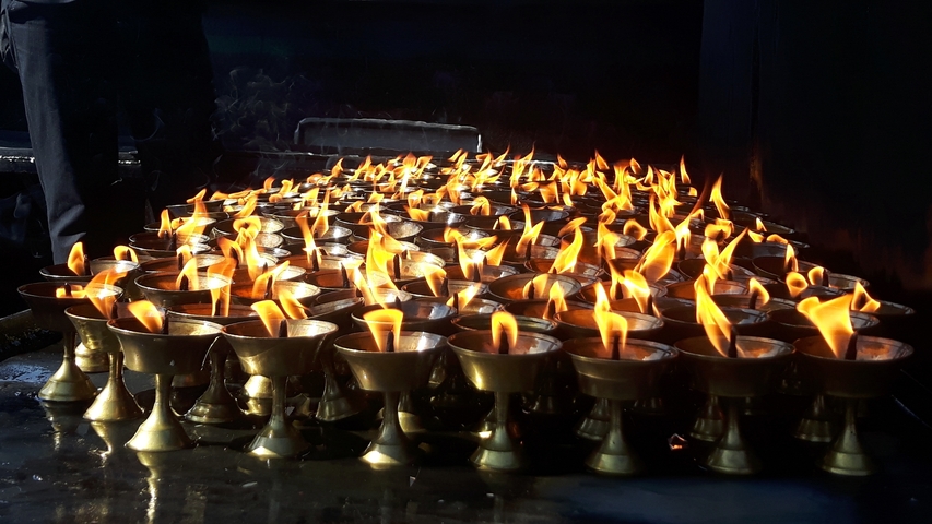       Several brass oil lamps with flames burning brightly.
  