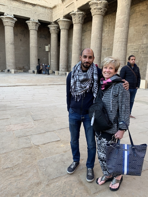 Two people standing in front of an ancient ruin.