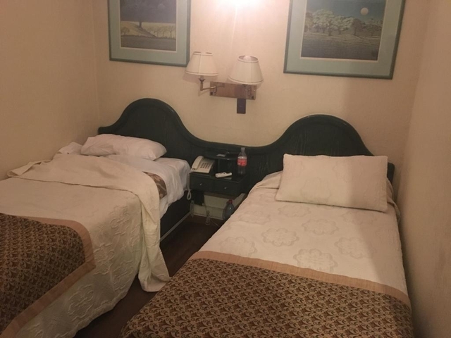 Simple hotel room with two beds and a nightstand.