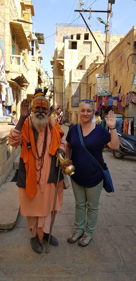 Woman posing with a sadhu in a vibrant street.