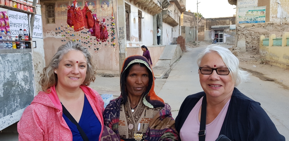 Two women posing with a local woman in traditional dress.