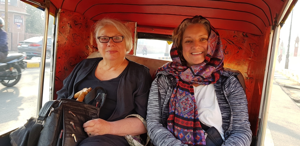       Two women inside a local tuk-tuk.
  
