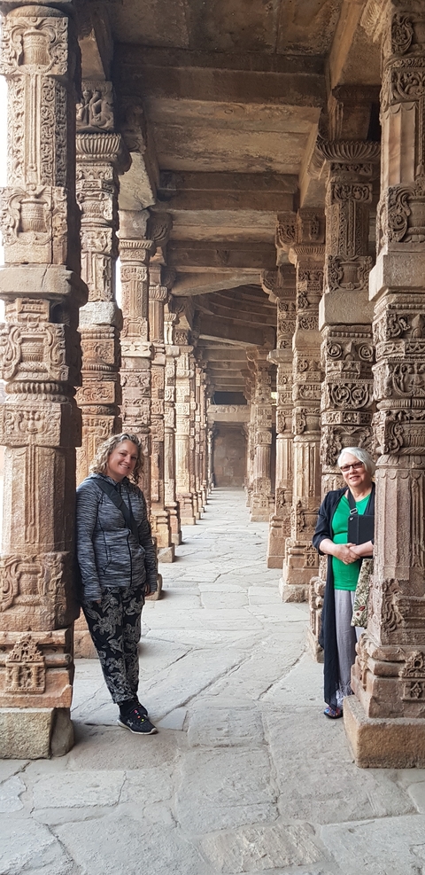       Two women in a columned corridor of an ancient structure.
  