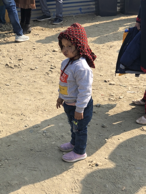       Young child standing on a rocky surface wearing casual clothes.
  