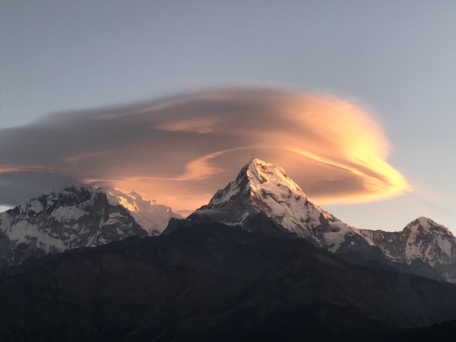 Snow-capped mountains with dramatic cloud formations at sunrise.