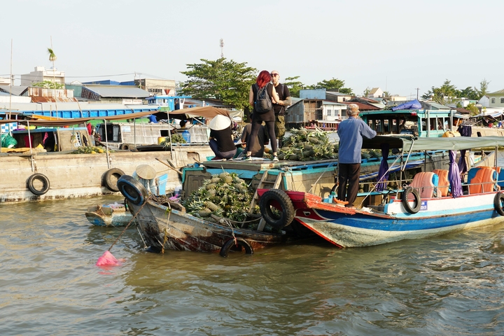 Busy floating market with people on boats carrying goods.