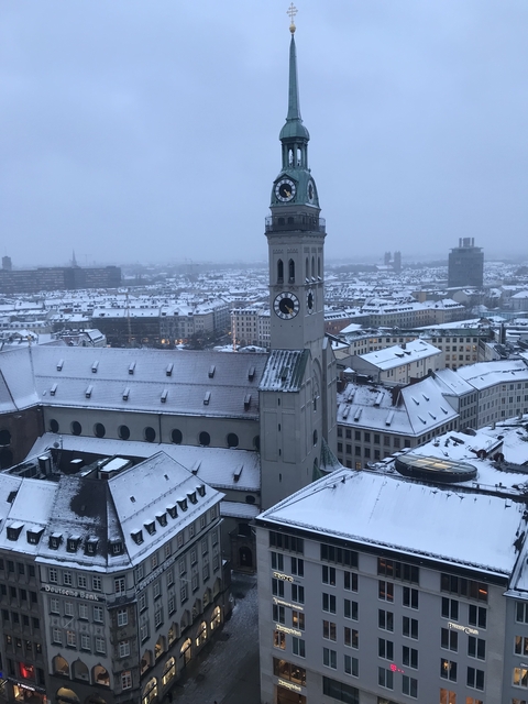 Cityscape with a clock tower amid snowy roofs.