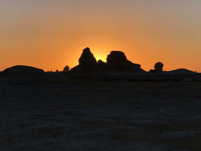 Sunset view with rock formations silhouetted against the sky.