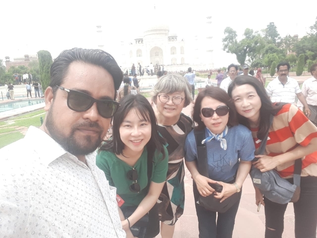 A group of people taking a selfie in front of the Taj Mahal.