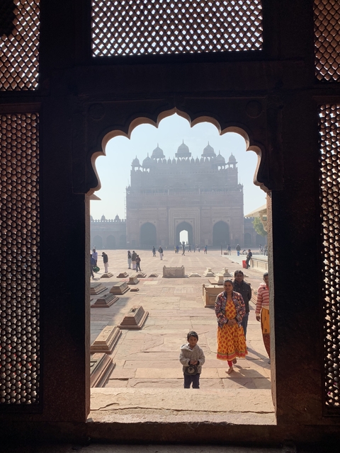 People walking in front of a historic stone building.
